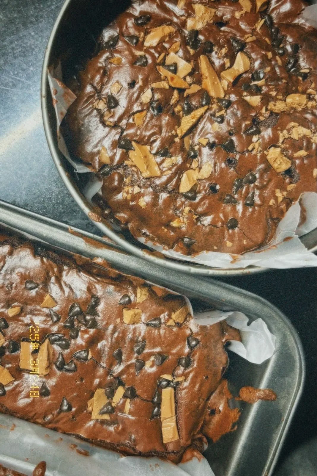 two trays of fudgy brownies with chocolate chips and toffee