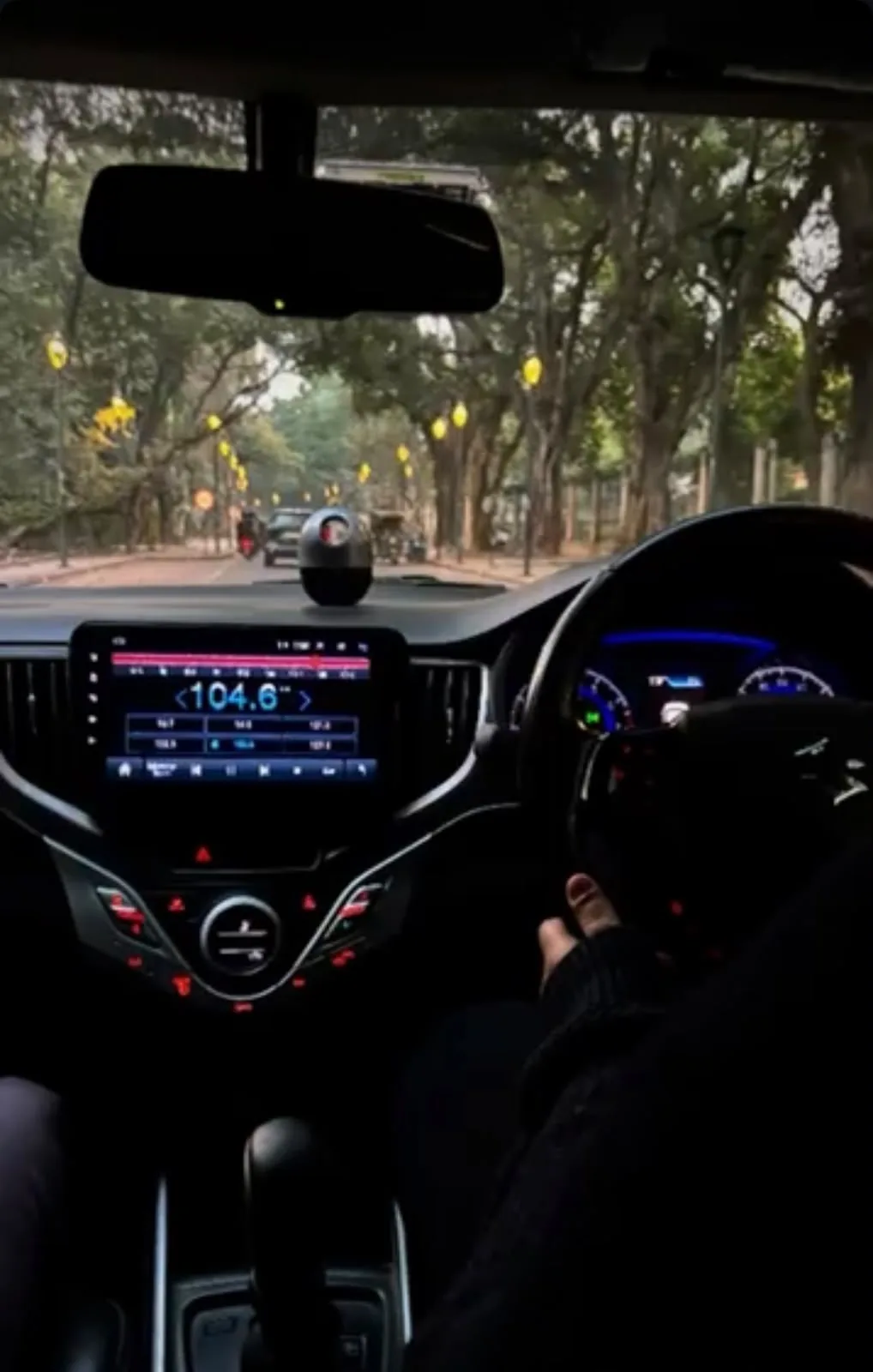 dashboard view, tree-lined road ahead, radio tuned to 104.6