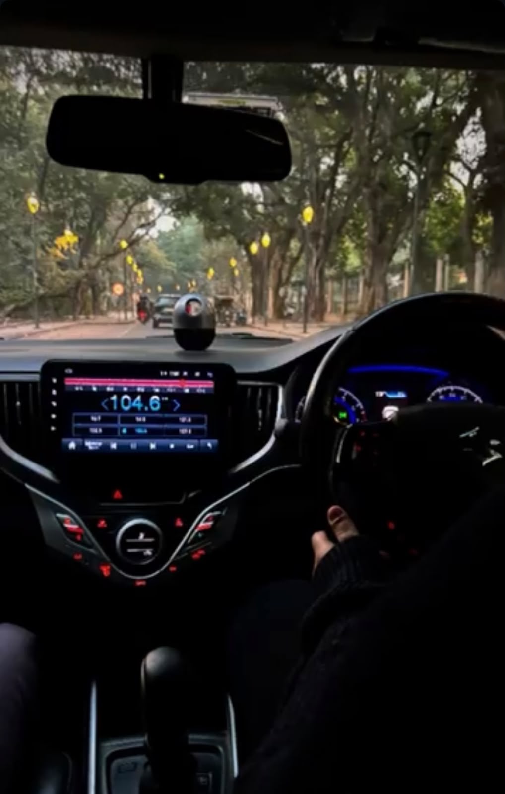 dashboard view, tree-lined road ahead, radio tuned to 104.6