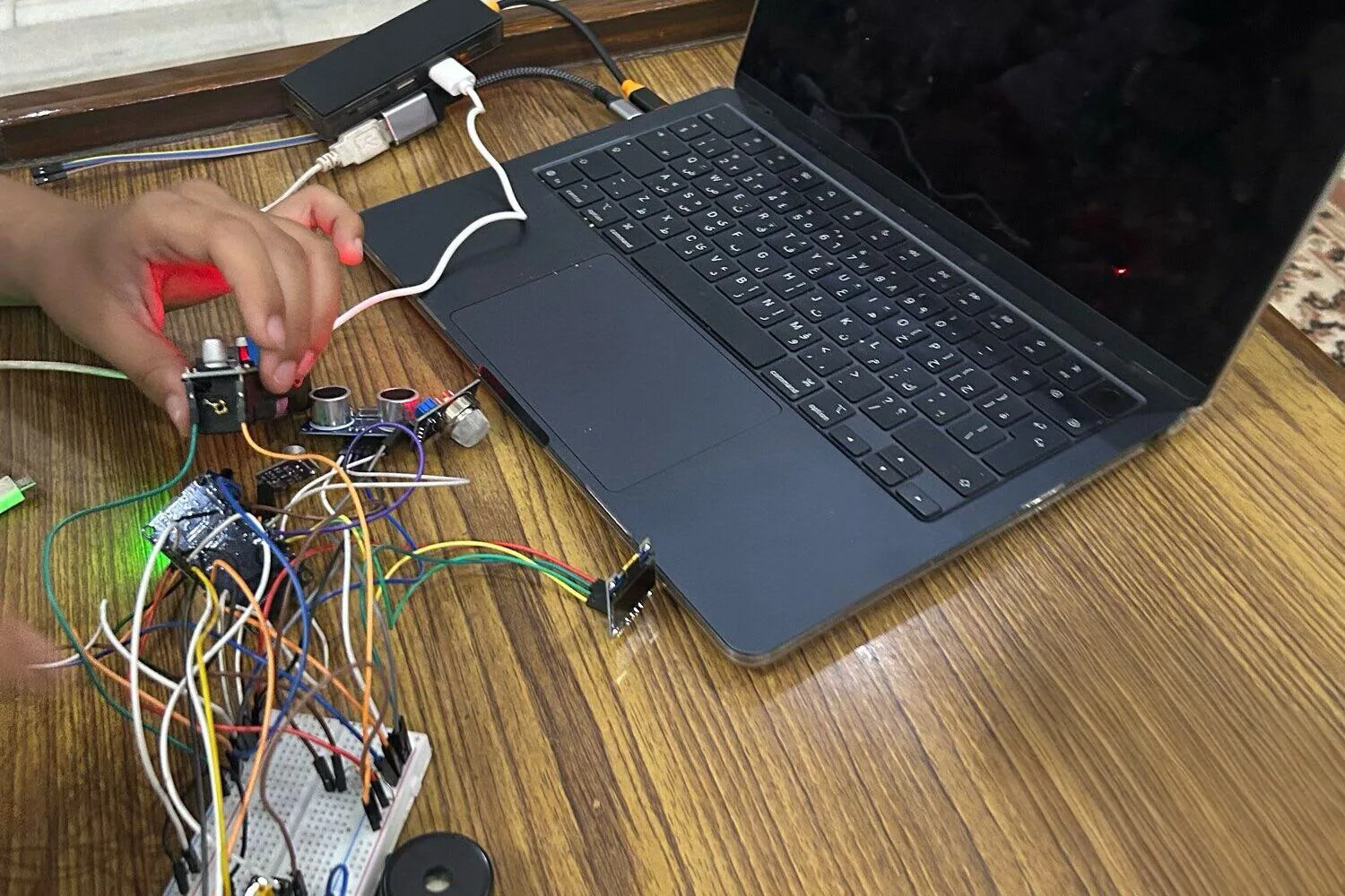 workbench with breadboard, jumper wires and laptop, mid-build