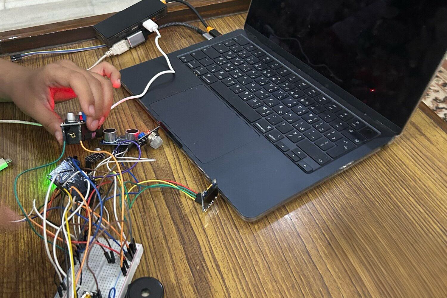 workbench with breadboard, jumper wires and laptop, mid-build